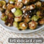 A beautifully plated dish of oven-roasted Brussels sprouts, elegantly topped with creamy goat cheese and a delicate drizzle of balsamic glaze.