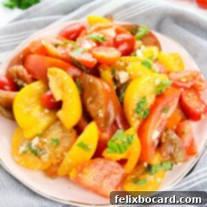 A vibrant Heirloom Tomato Salad, featuring colorful slices of ripe heirloom tomatoes, fresh herbs, and a crumble of feta cheese.
