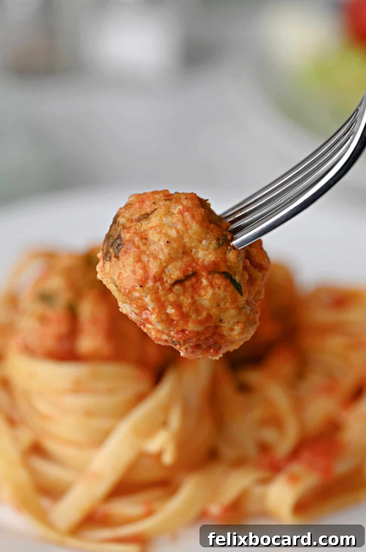 A fork holding a perfectly cooked chicken ricotta meatball, ready to be enjoyed.