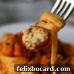 Bitten chicken ricotta meatball on a fork with marinara coated pasta.