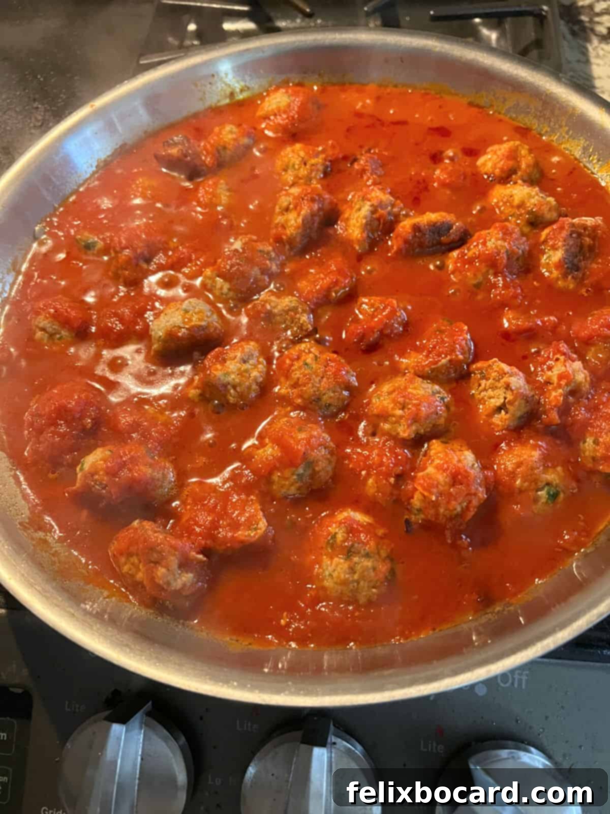 Cooked chicken ricotta meatballs nestled in a rich marinara sauce in a large skillet, bubbling gently.