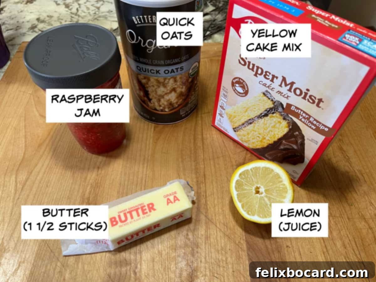 A flat lay photograph showcasing the five essential ingredients: a box of cake mix, quick oats, raspberry jam, a stick of butter, and a fresh lemon.