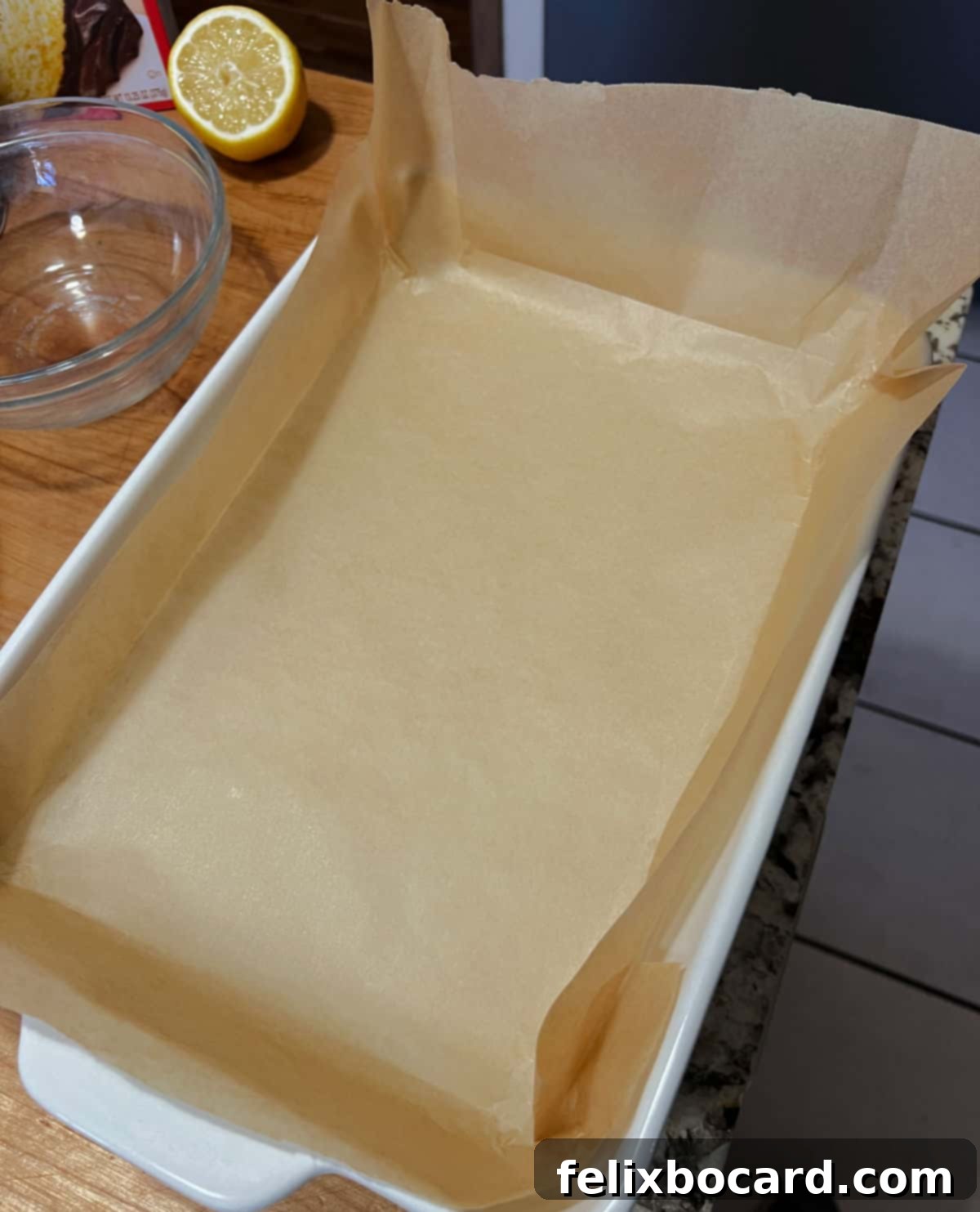 A 9x13 inch baking pan neatly lined with parchment paper, extending over the sides.