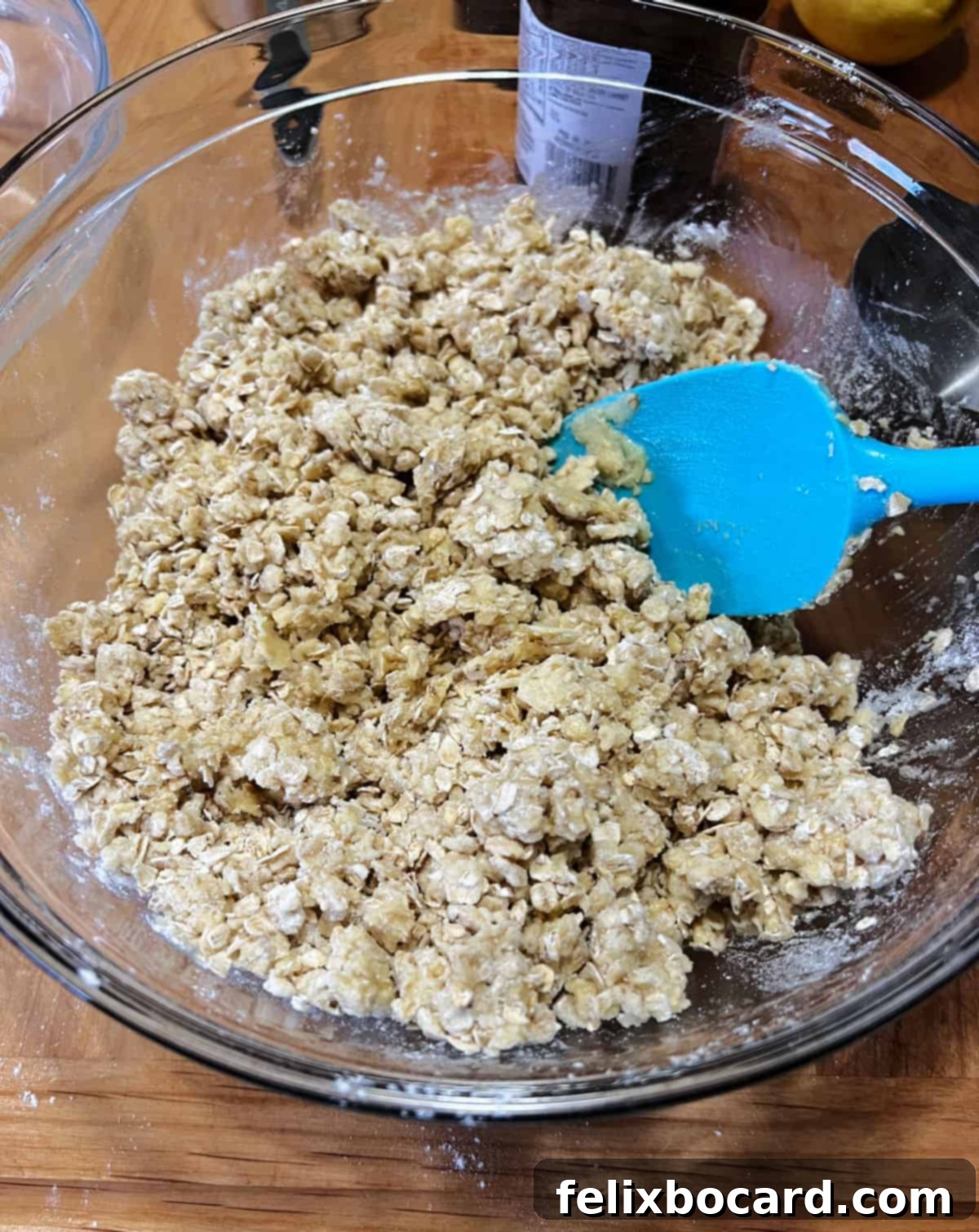 Close-up of a mixing bowl containing the clumpy mixture of cake mix, oats, and butter, indicating it's well combined.
