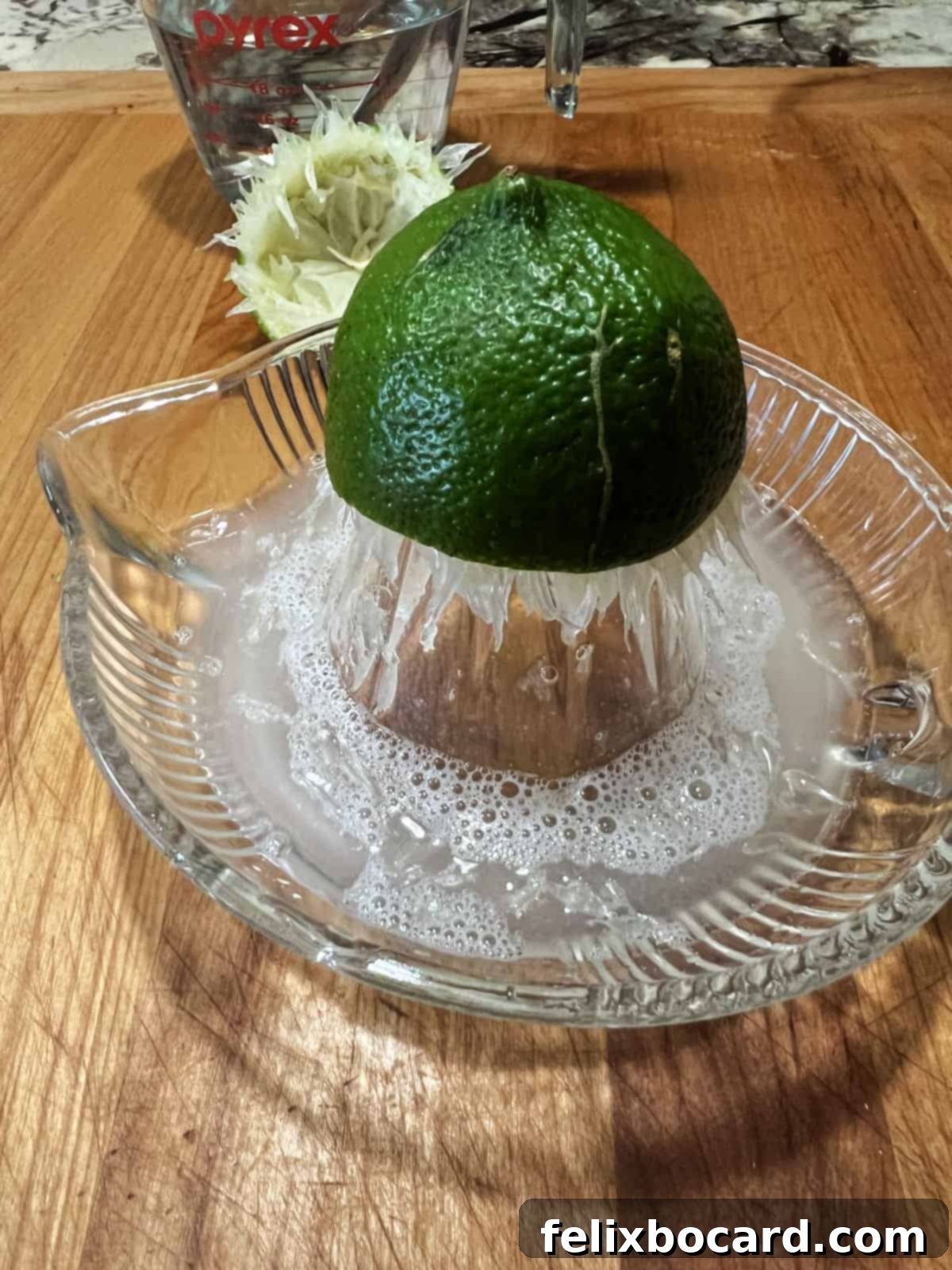 Squeezing fresh juice from half a lime into a measuring cup.