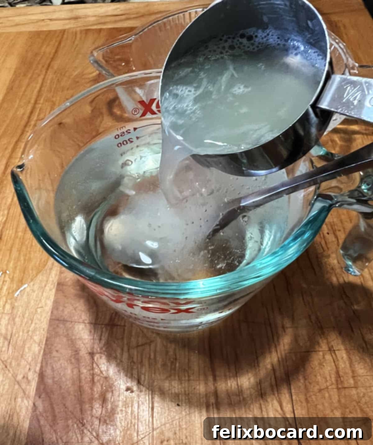 Adding fresh lime juice to the sugar water mixture in a measuring cup.