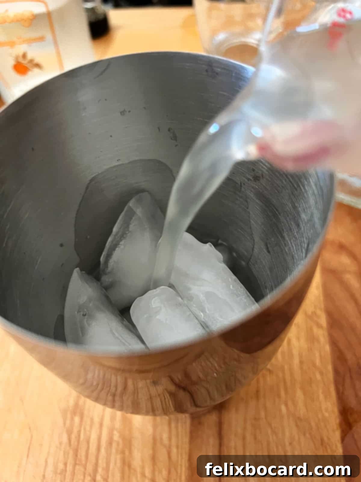 Pouring the measured ingredients, Patron tequila, orange liqueur, and sweet and sour mix, into a cocktail shaker filled with ice.