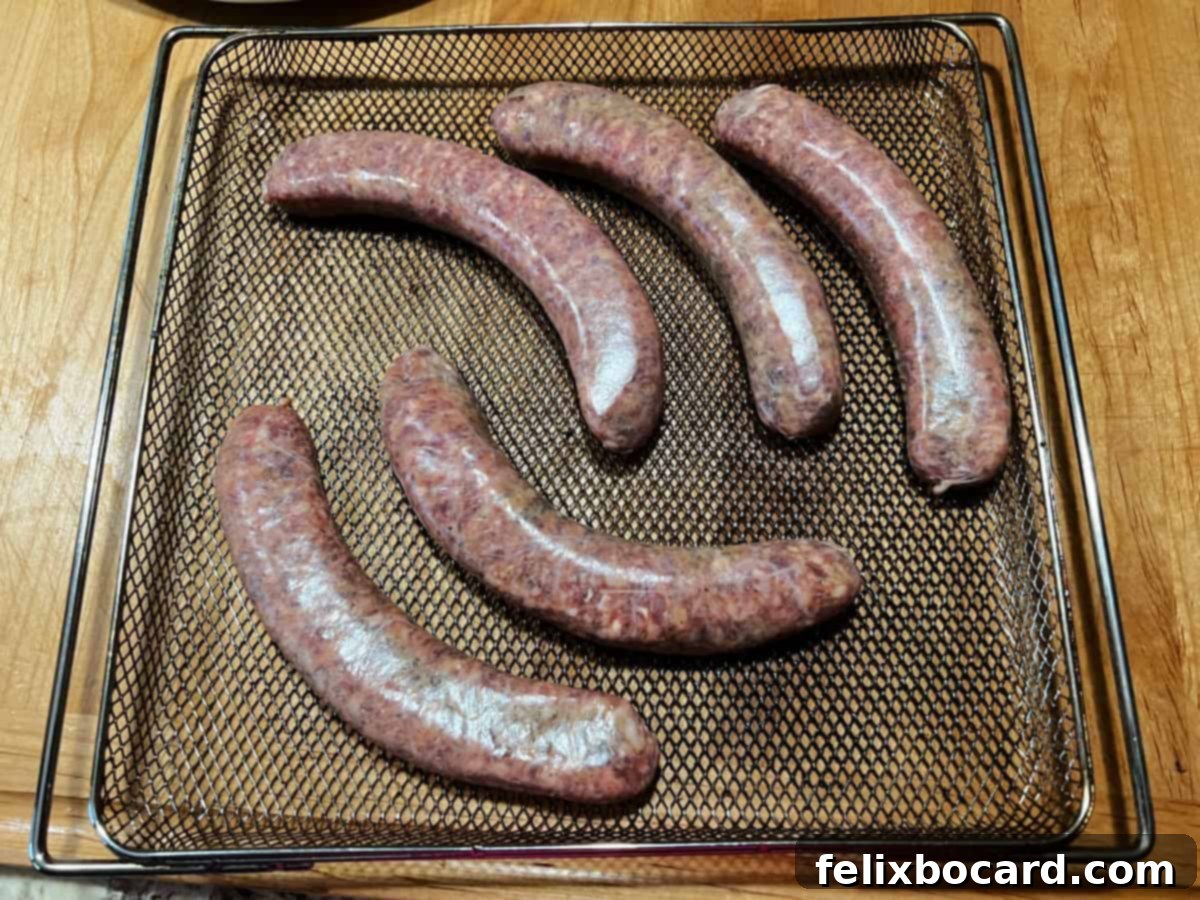 Raw Italian sausages neatly spread out in a single layer on an air fryer basket, ready for cooking.