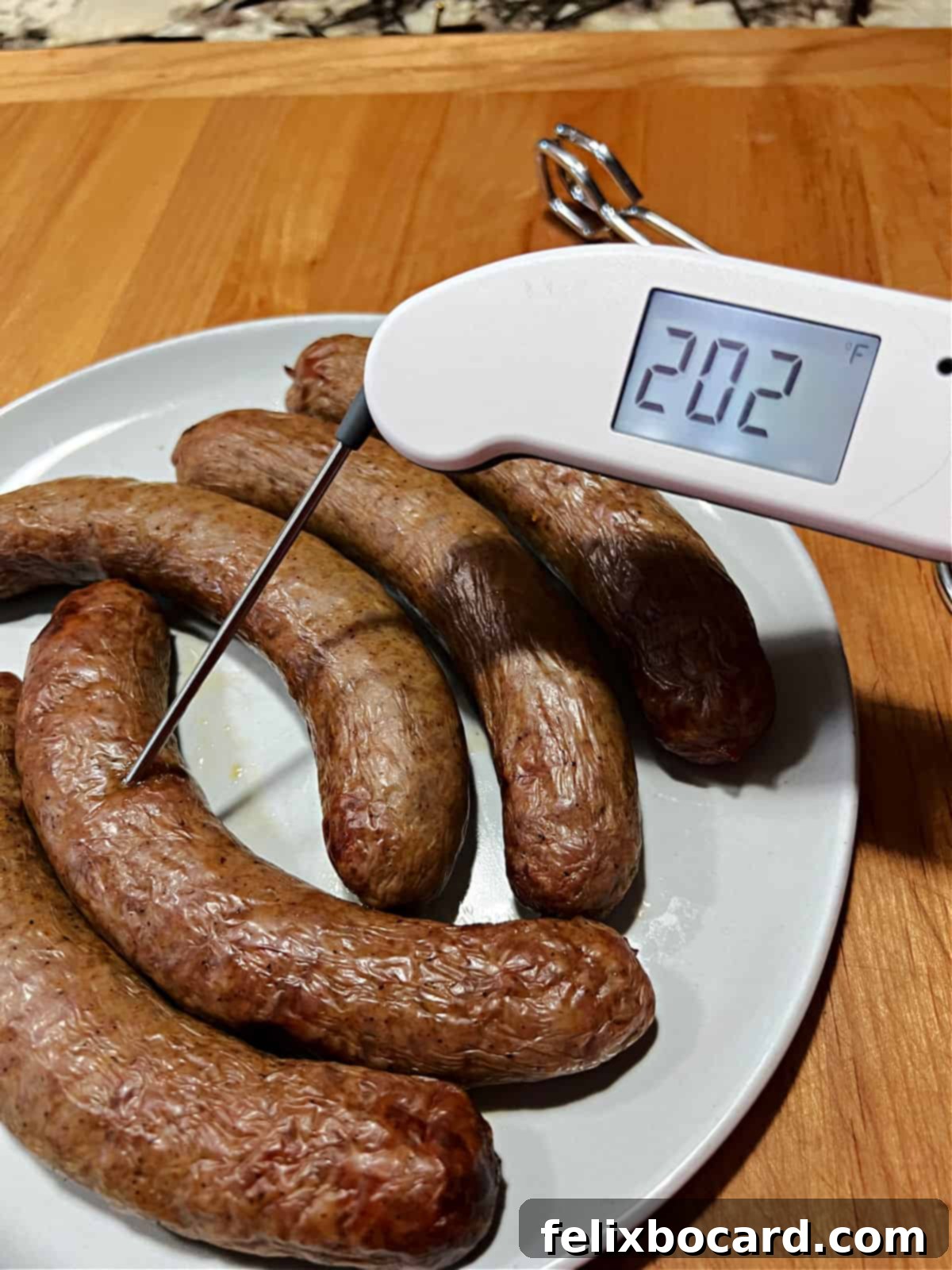 A digital meat thermometer inserted into a cooked Italian sausage, displaying the internal temperature.