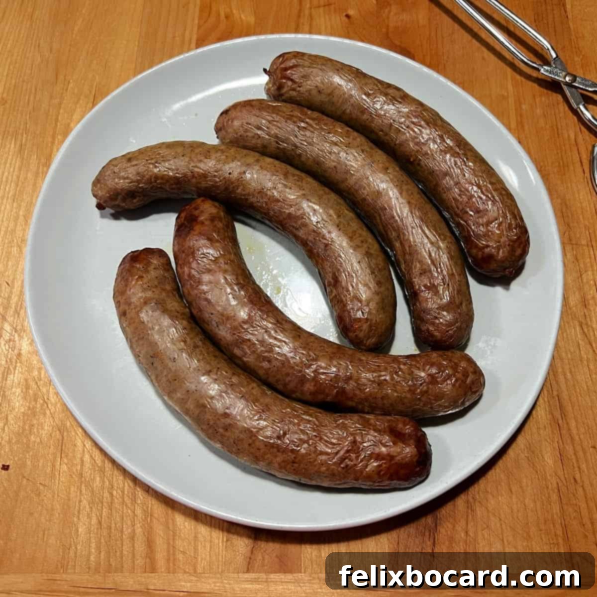 A plate of 5 golden-brown Italian sausages, fresh from the air fryer and ready to be served.