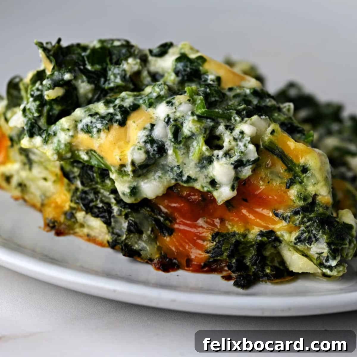 A generous serving of cheesy spinach casserole, presented beautifully and ready to be enjoyed.
