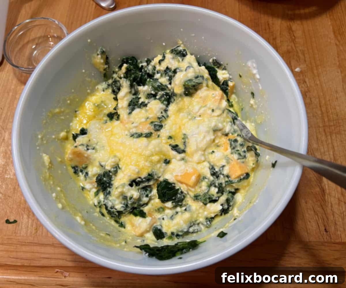 Adding the prepared spinach to the cheesy cottage cheese and egg mixture.