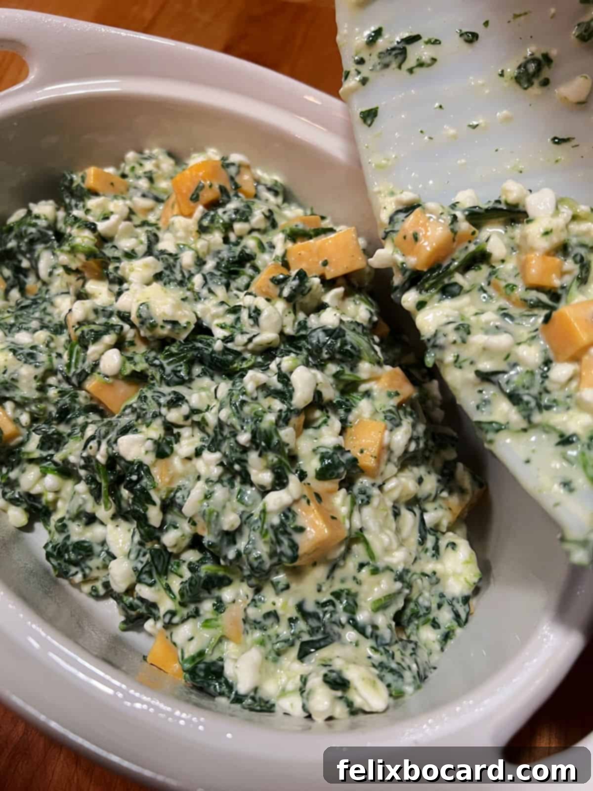 Transferring the cheesy spinach mixture into a greased casserole dish, ready for baking.