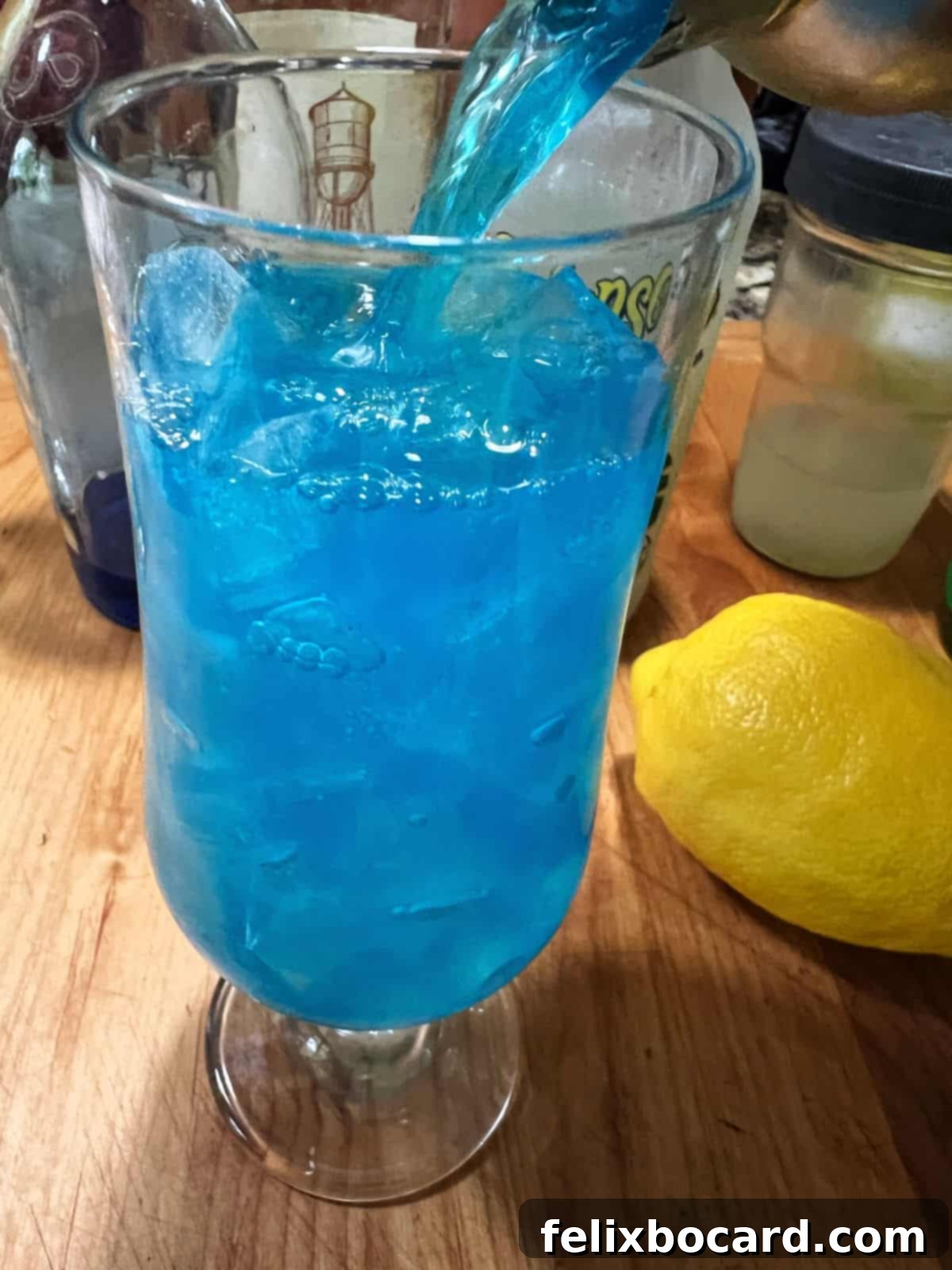 Pouring the vibrant blue electric lemonade into an ice-filled glass.