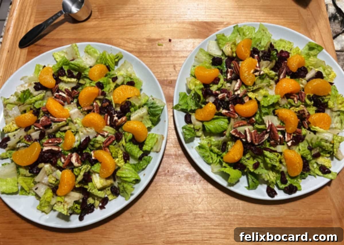 Assembling the salads by adding cranberries, mandarin oranges, pecan pieces, and blue cheese to the greens.