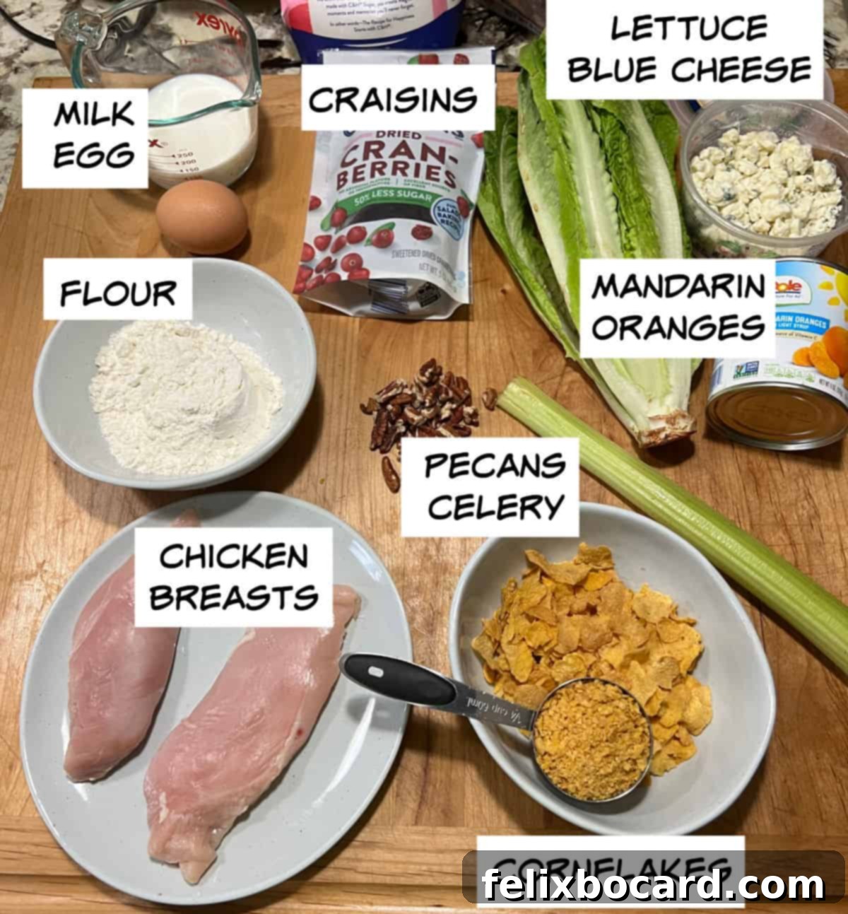 Fresh ingredients: milk, egg, flour, boneless skinless chicken breasts, crushed cornflakes, chopped pecans, crisp celery, bright mandarin oranges, sweet dried cranberries (Craisins), crumbled blue cheese, and vibrant lettuce.