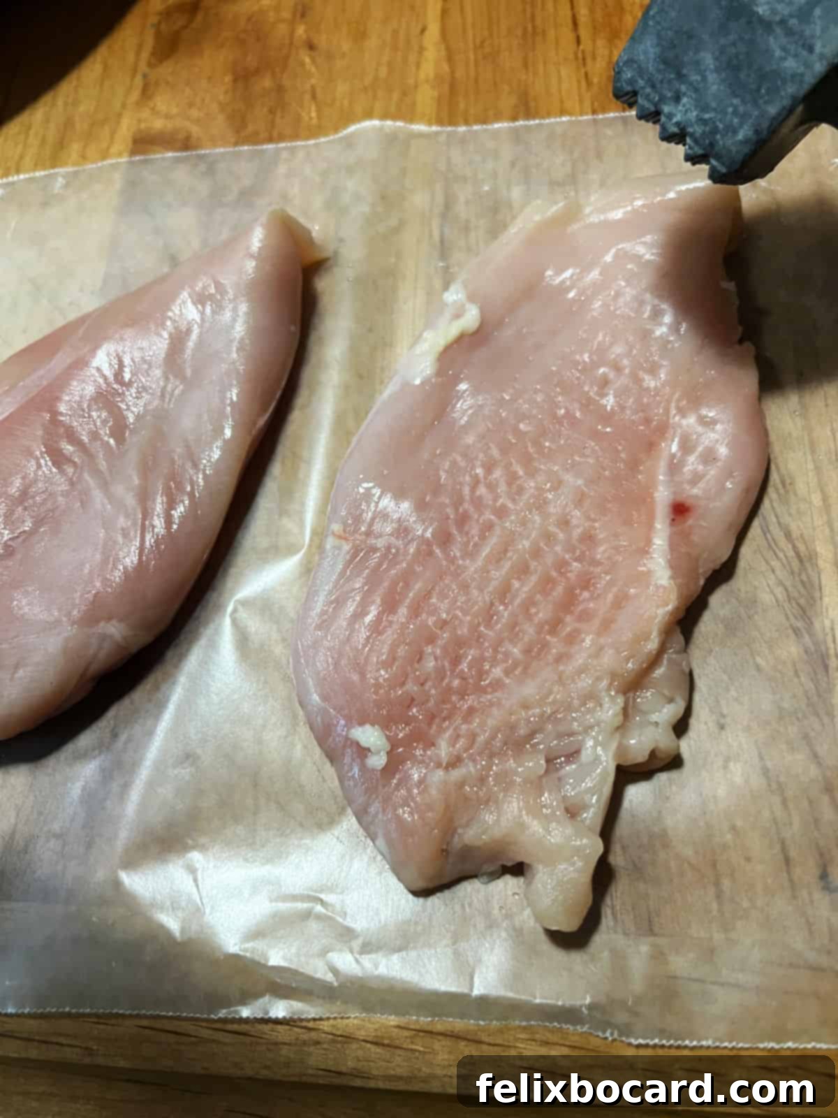 Pounding chicken breasts with a meat mallet to achieve an even thickness.
