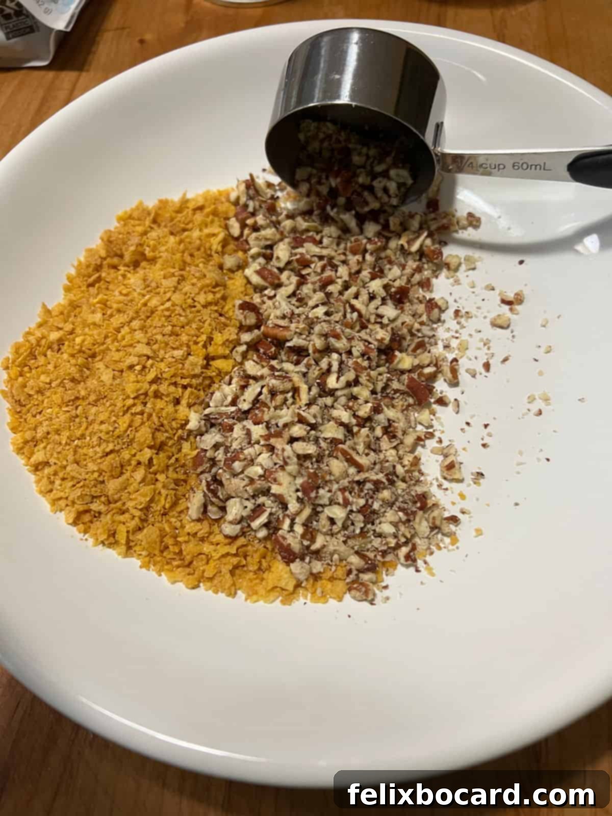 Crushed cornflakes and chopped pecans mixed together in a shallow bowl, ready for the chicken coating.