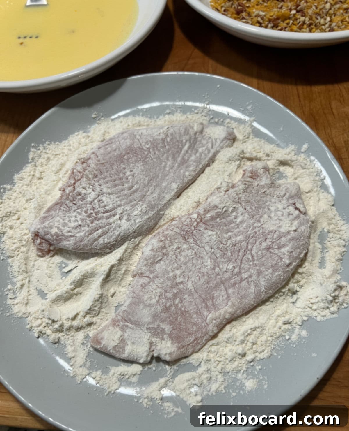 Chicken breast fully coated in flour, ready for the next step.
