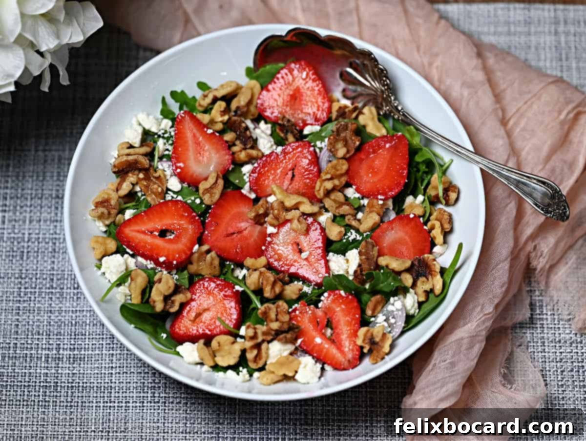 Vibrant Arugula and Spinach Salad with fresh strawberries, crumbled feta, and walnuts, drizzled with balsamic vinaigrette, ready to be served.