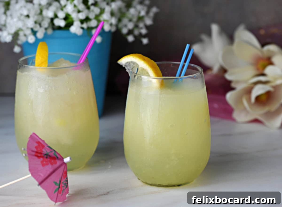 Two elegant glasses brimming with a vibrant frozen lemonade slush, garnished with fresh lemon slices and ready to be enjoyed on a sunny day.
