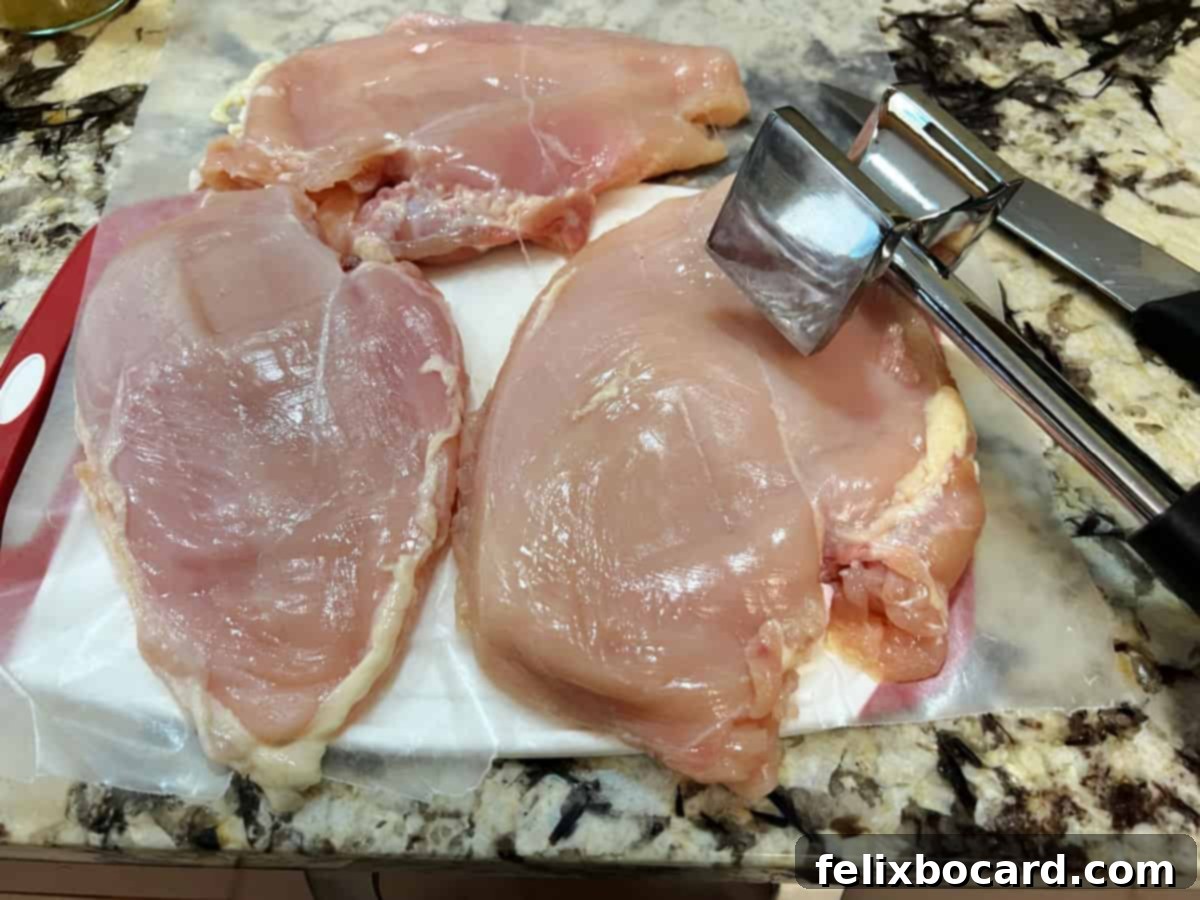 Pounding chicken breasts flat.