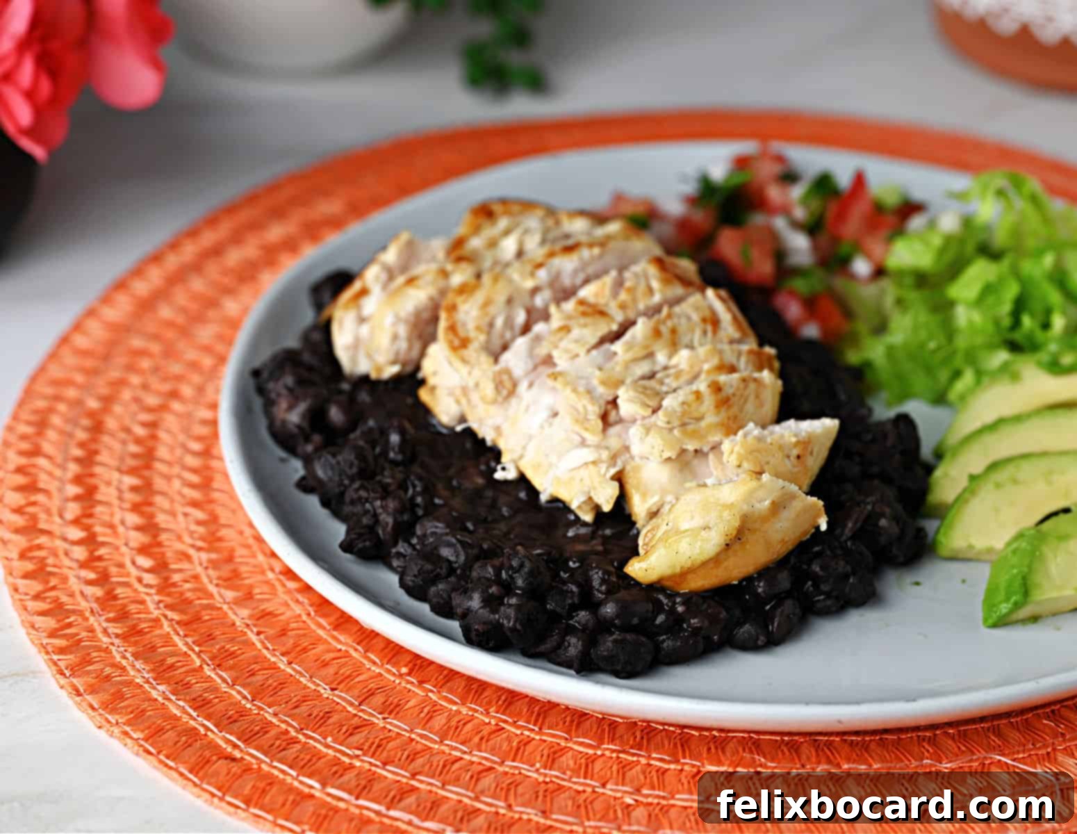 Grilled margarita chicken on a plate of black beans.