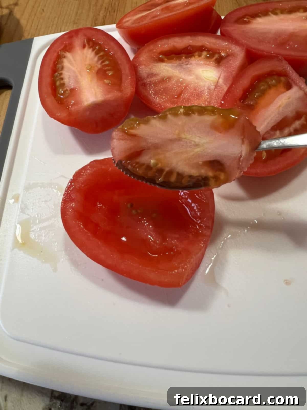 Avocado Pico de Gallo 4 Scooping out the insides from a Roma tomato to prepare it for dicing.
