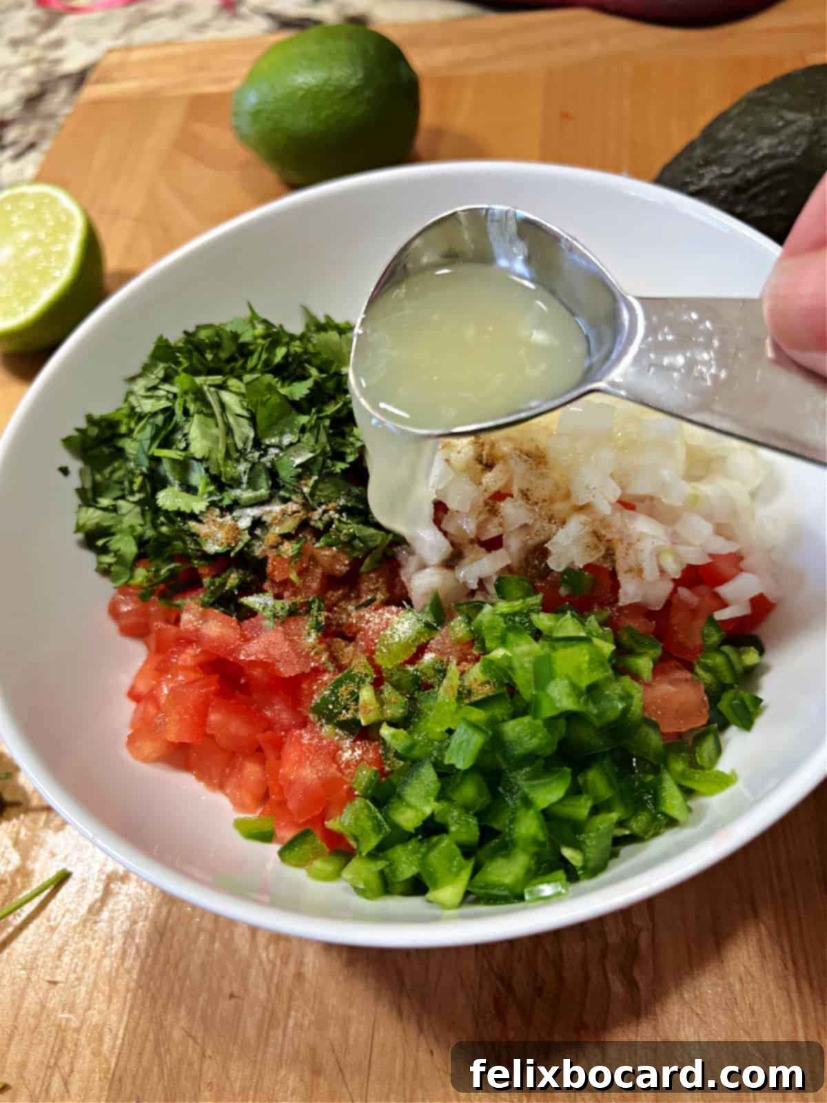 Avocado Pico de Gallo 5 Chopped tomatoes, onion, cilantro, and jalapeno in a bowl, with fresh lime juice being squeezed over them.