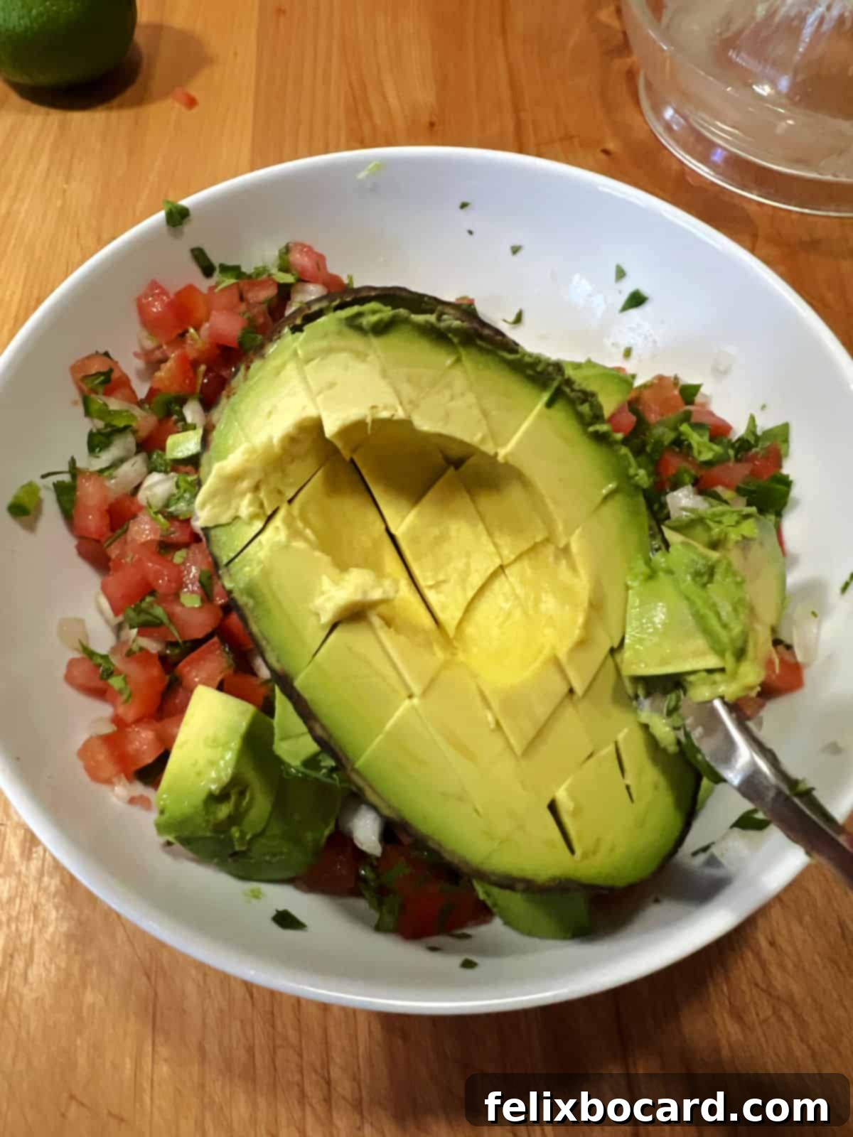 Avocado Pico de Gallo 7 Scooping perfectly diced avocado out of its skin to add to the prepared Pico de Gallo.