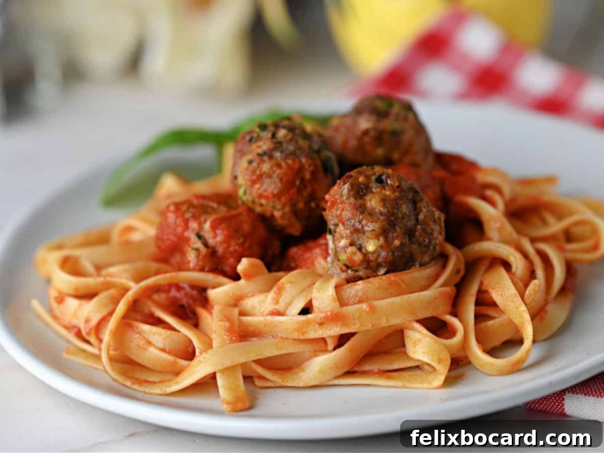 Garden Fresh Beef & Zucchini Meatballs 12 A generous serving of zucchini meatballs in sauce on fettuccine noodles, ready to be enjoyed.