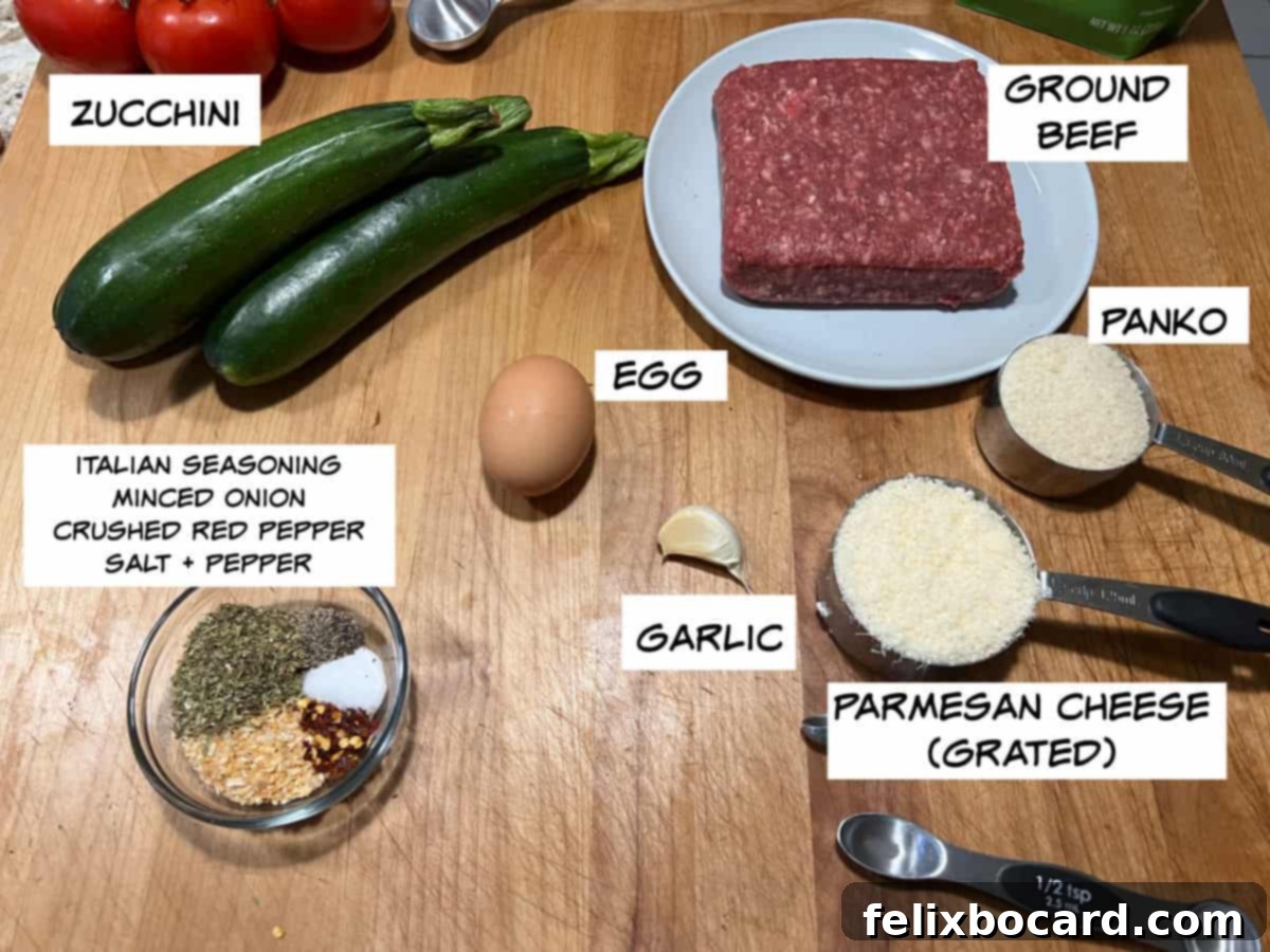 Garden Fresh Beef & Zucchini Meatballs 3 A flat lay photograph showcasing all the ingredients for zucchini meatballs: zucchini, ground beef, panko breadcrumbs, Parmesan cheese, an egg, minced garlic, and a selection of spices including Italian seasoning, dried minced onion, crushed red pepper flakes, salt, and black pepper.