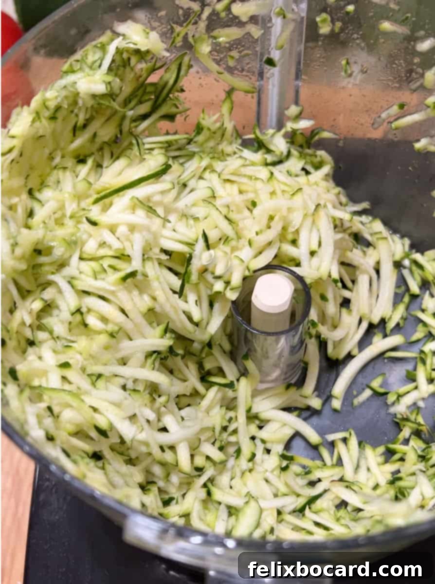 Garden Fresh Beef & Zucchini Meatballs 4 Shredded zucchini collected in a food processor bowl, illustrating the finely grated texture ideal for meatballs.