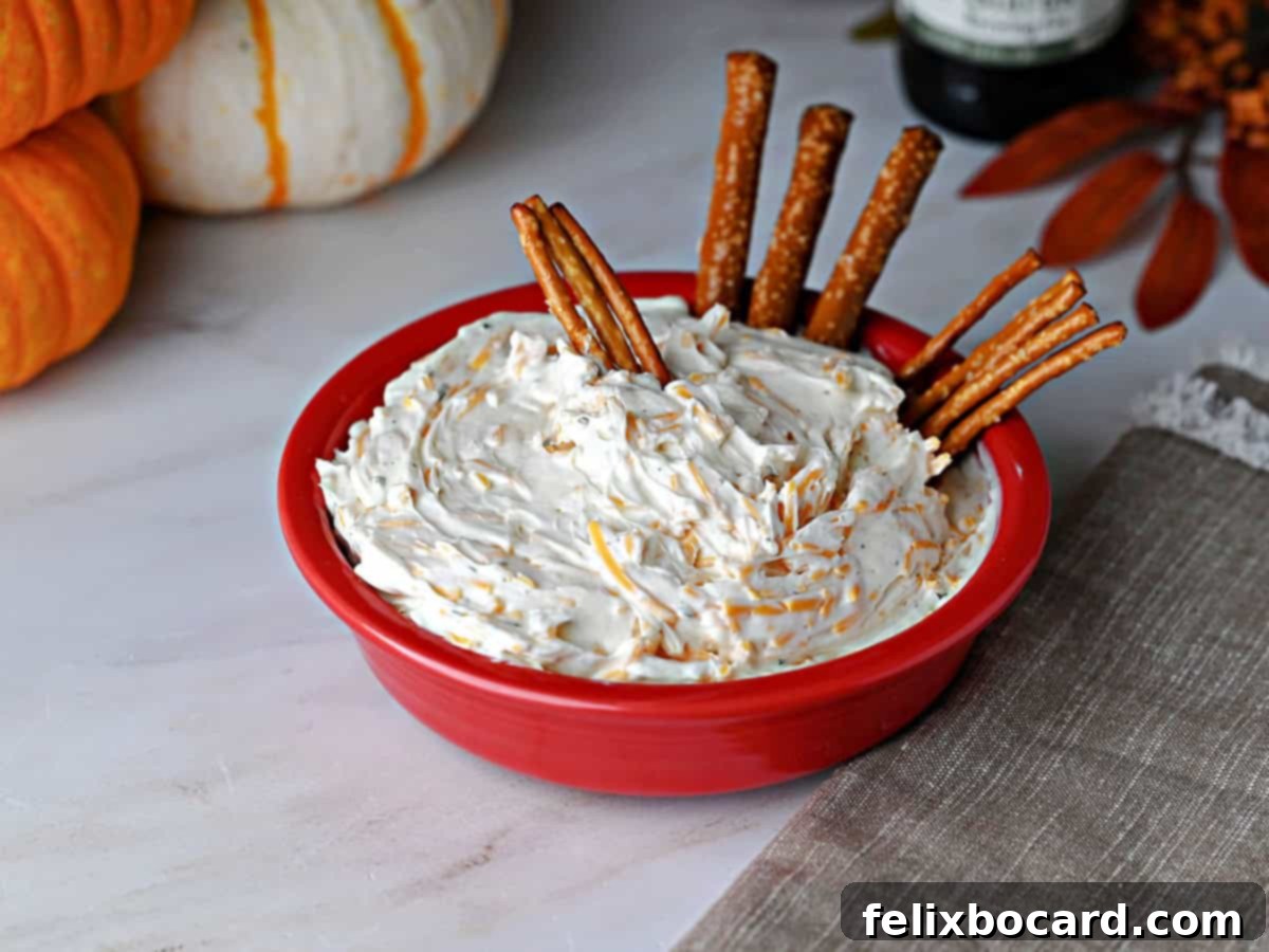 A vibrant red bowl filled with creamy Beer Cheese Dip, perfectly paired with crunchy pretzels for a classic game day snack.