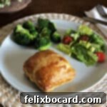 chicken in puff pastry hand pie on a plate with salad and broccoli