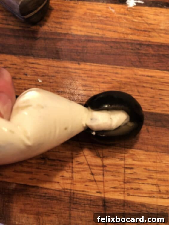 Penguin Party Bites 5 Detailed shot showing a jumbo black olive with a wedge cut and filled with whipped cream cheese to create the penguin's white belly.