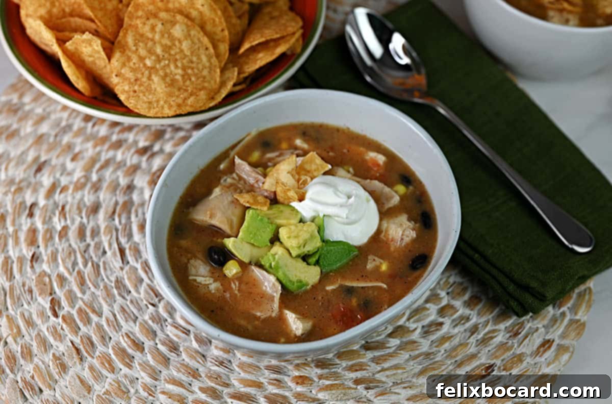 Bowl of chicken tortilla soup made with Rotel, garnished with sour cream and avocado.