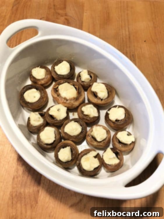 oval dish with mushroom caps, brie pieces put in each