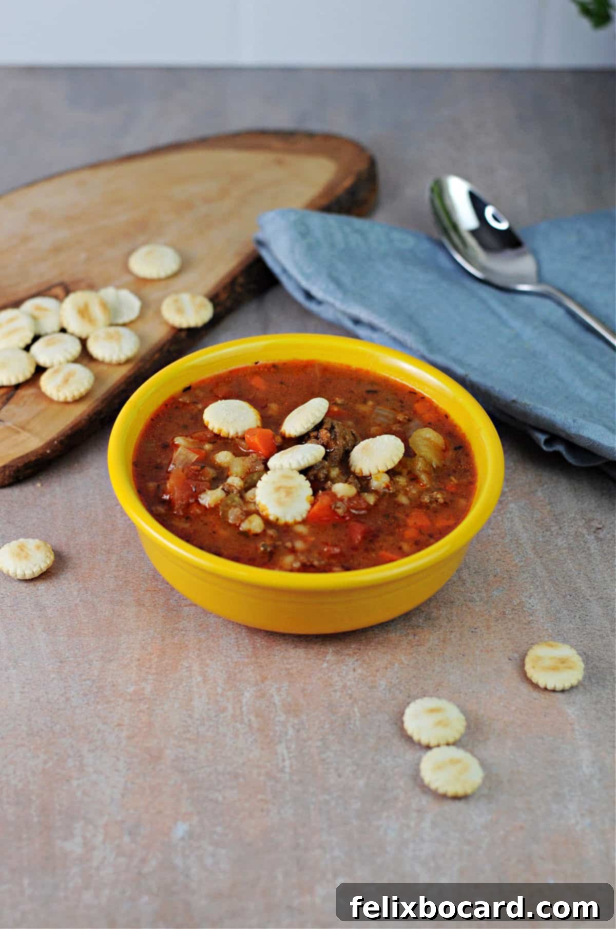Ground Beef Barley Soup 2 Small yellow bowl of hearty hamburger barley soup, garnished with fresh parsley.
