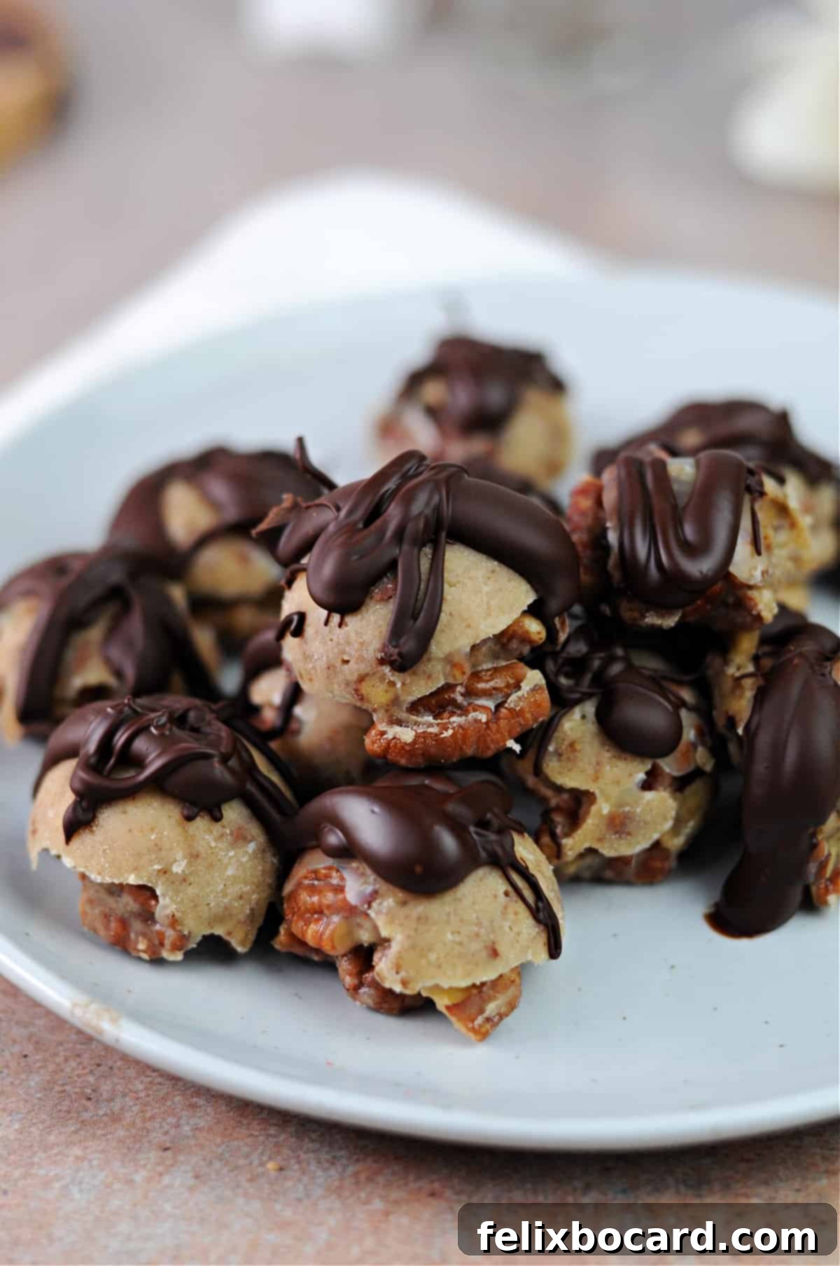 Irresistible chocolate drizzled keto pecan clusters on a small plate, perfect for a low-carb treat.