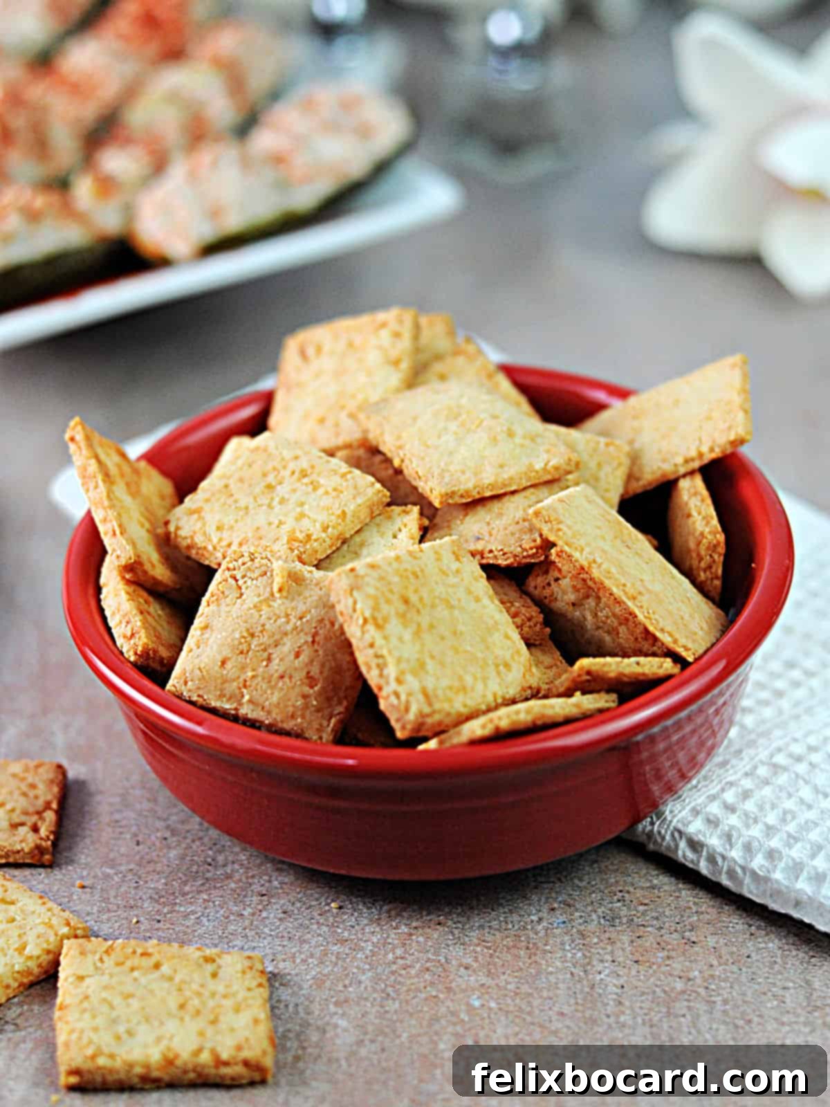 A vibrant red bowl overflowing with golden, crispy keto snack crackers, ready to be enjoyed.