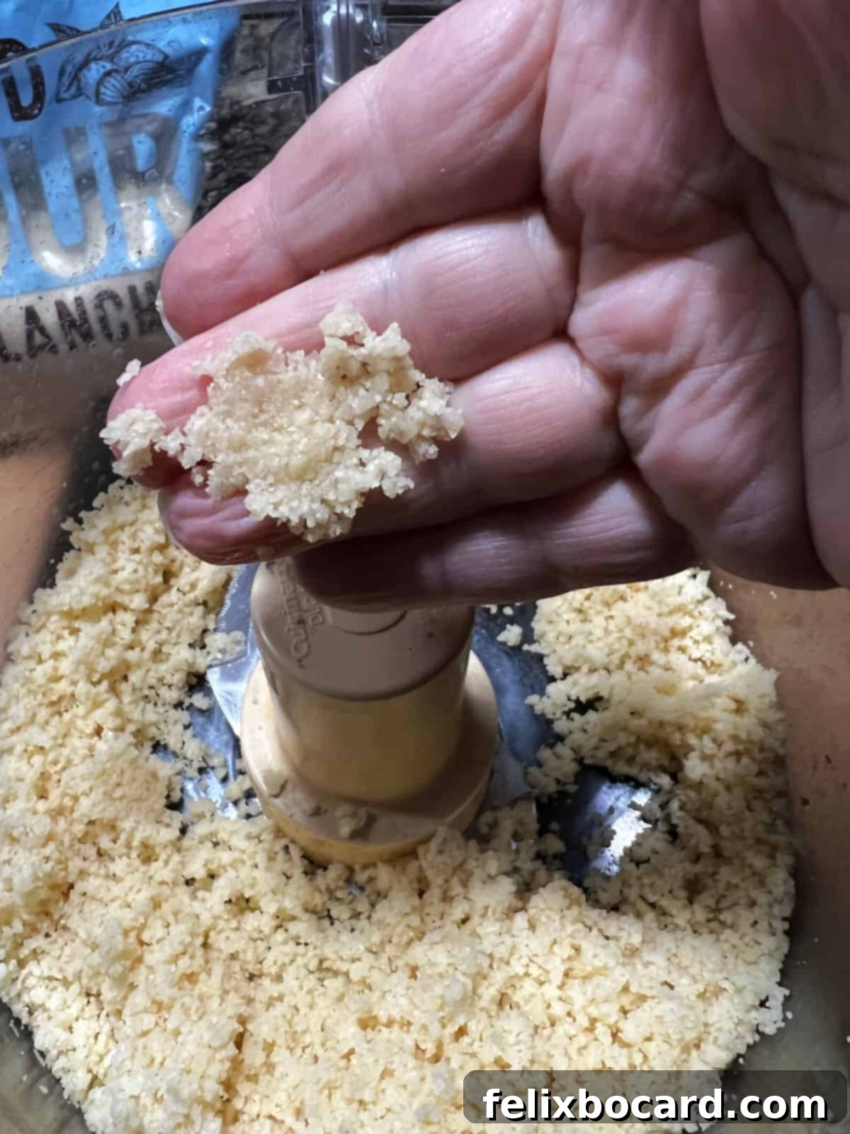 A hand gently squeezing a small ball of keto cracker dough, demonstrating its ideal sticky and cohesive consistency.