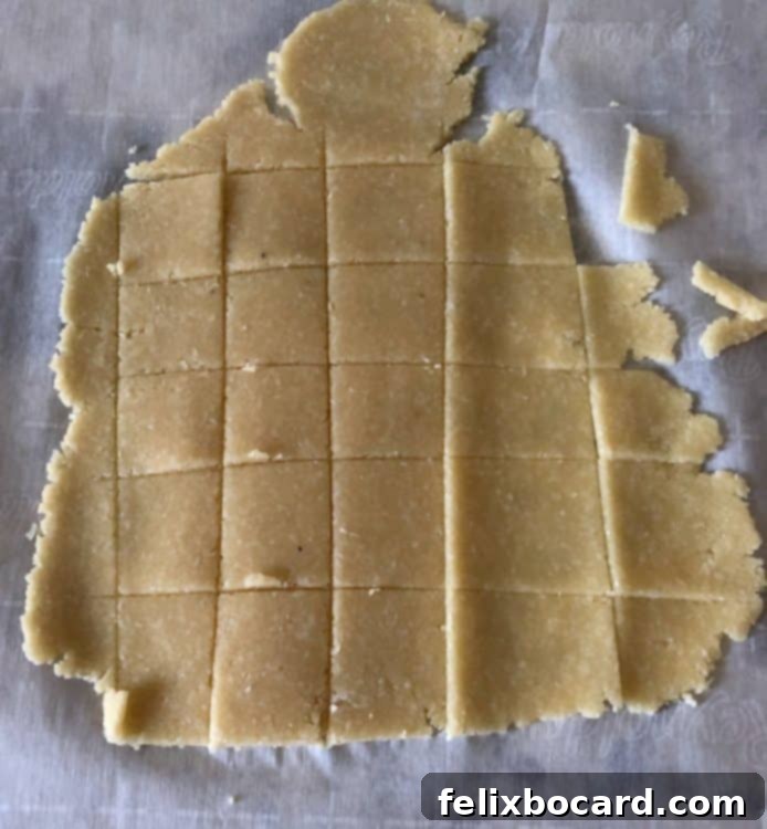 Rolled-out keto cracker dough meticulously cut into precise squares using a pizza cutter, ready for baking.