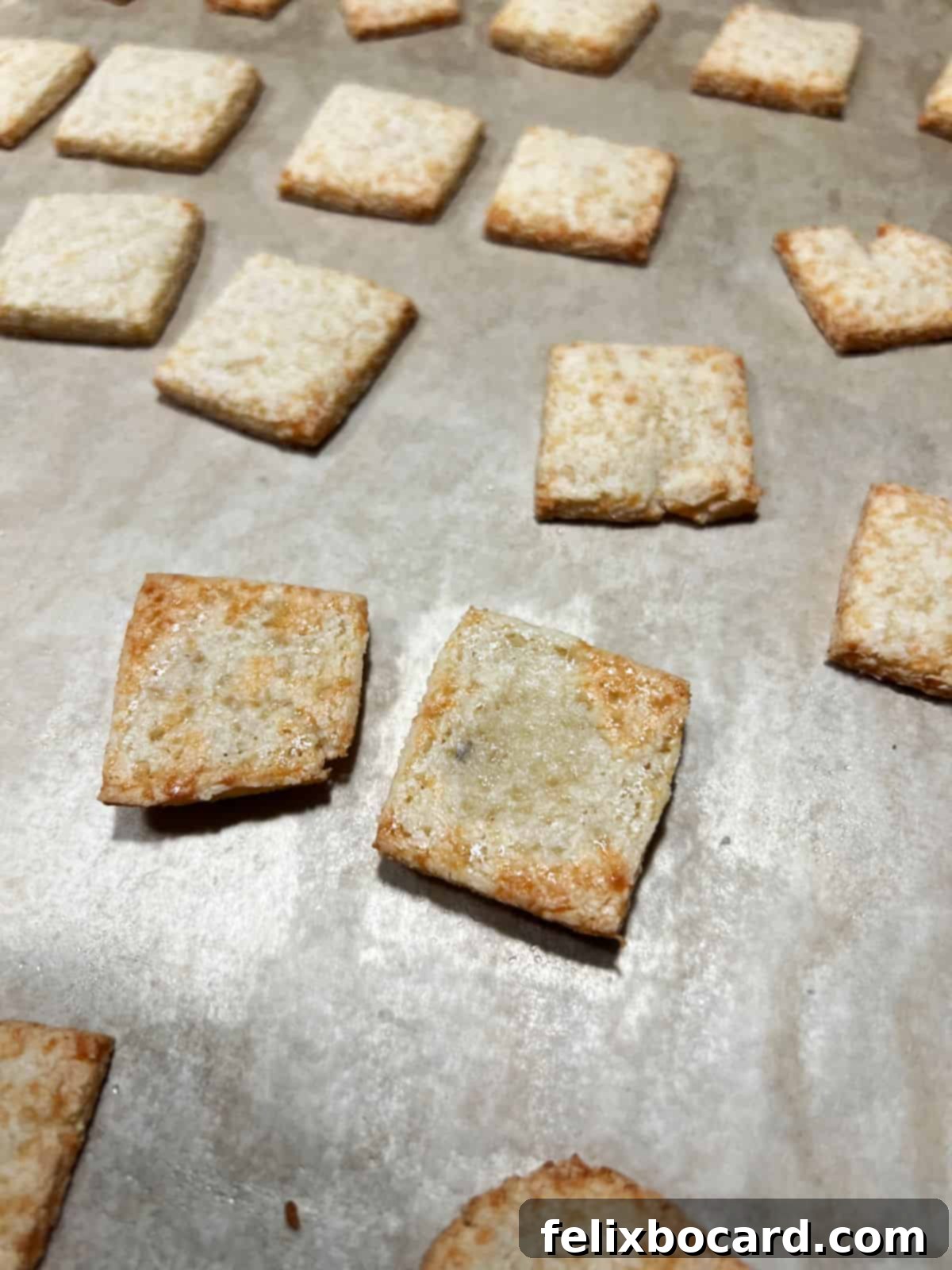 A baking sheet filled with keto crackers, freshly flipped to achieve even golden crispness during the final minutes of baking.
