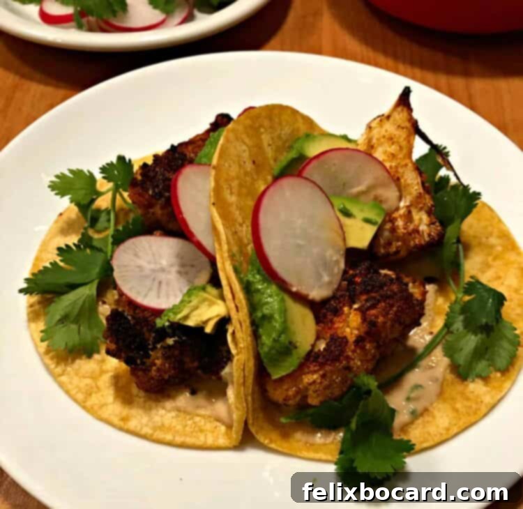 Two vibrant cauliflower tacos served on a white plate, showcasing their deliciousness