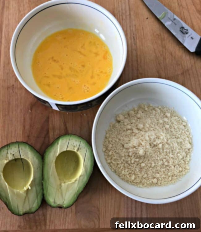 one bowl with beaten egg and another with almond meal next to a cut avocado