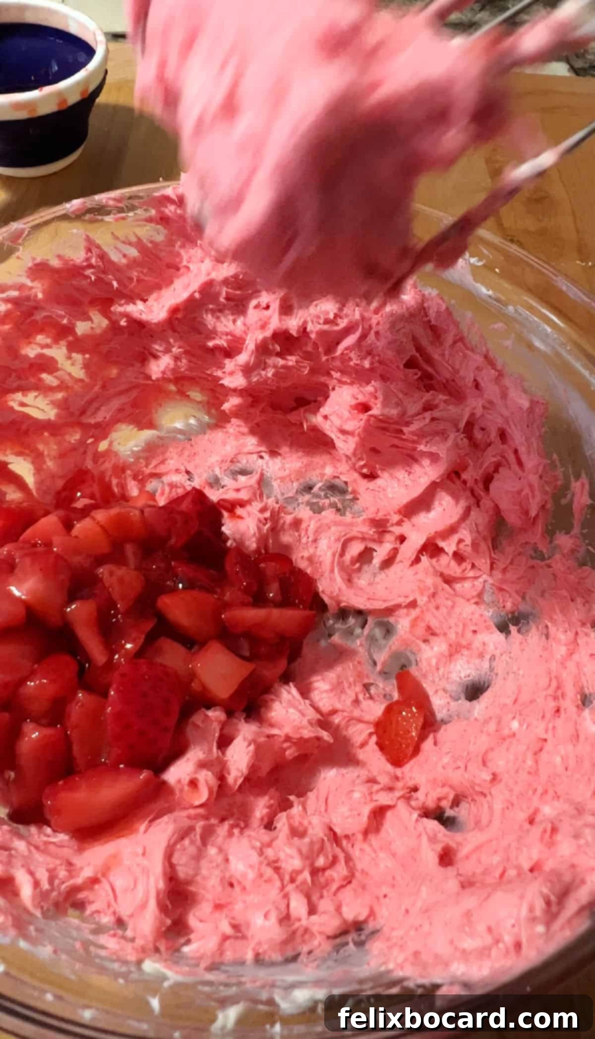 ingredients getting mixed in a bowl by a hand mixer.