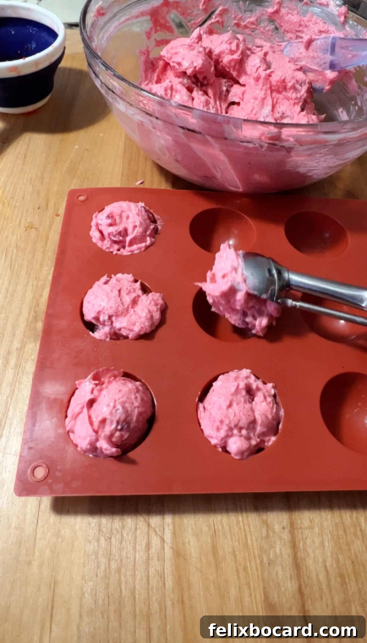 scooping strawberry mixture into a silicone mold with a cookie scoop.