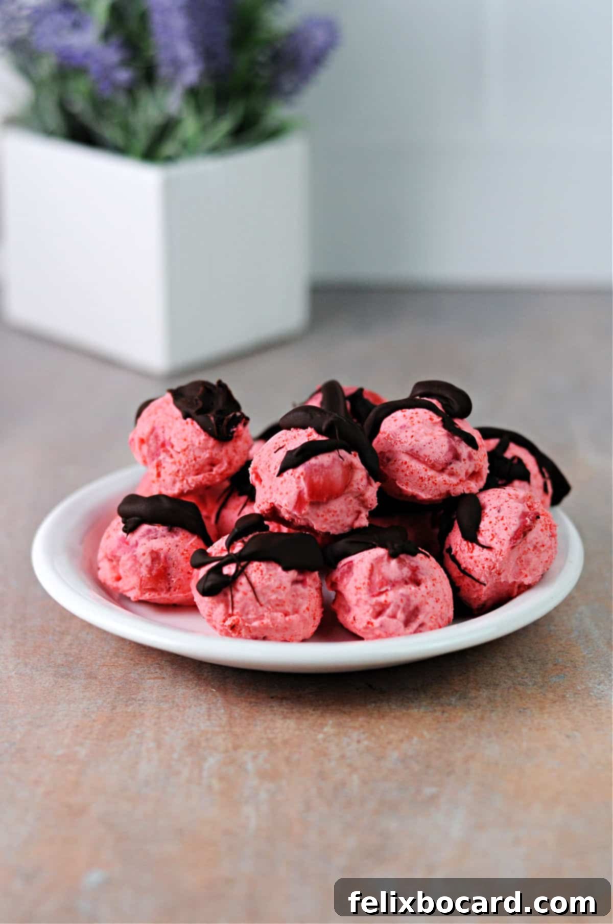 pile of chocolate drizzled keto strawberry fat bombs on a small plate.