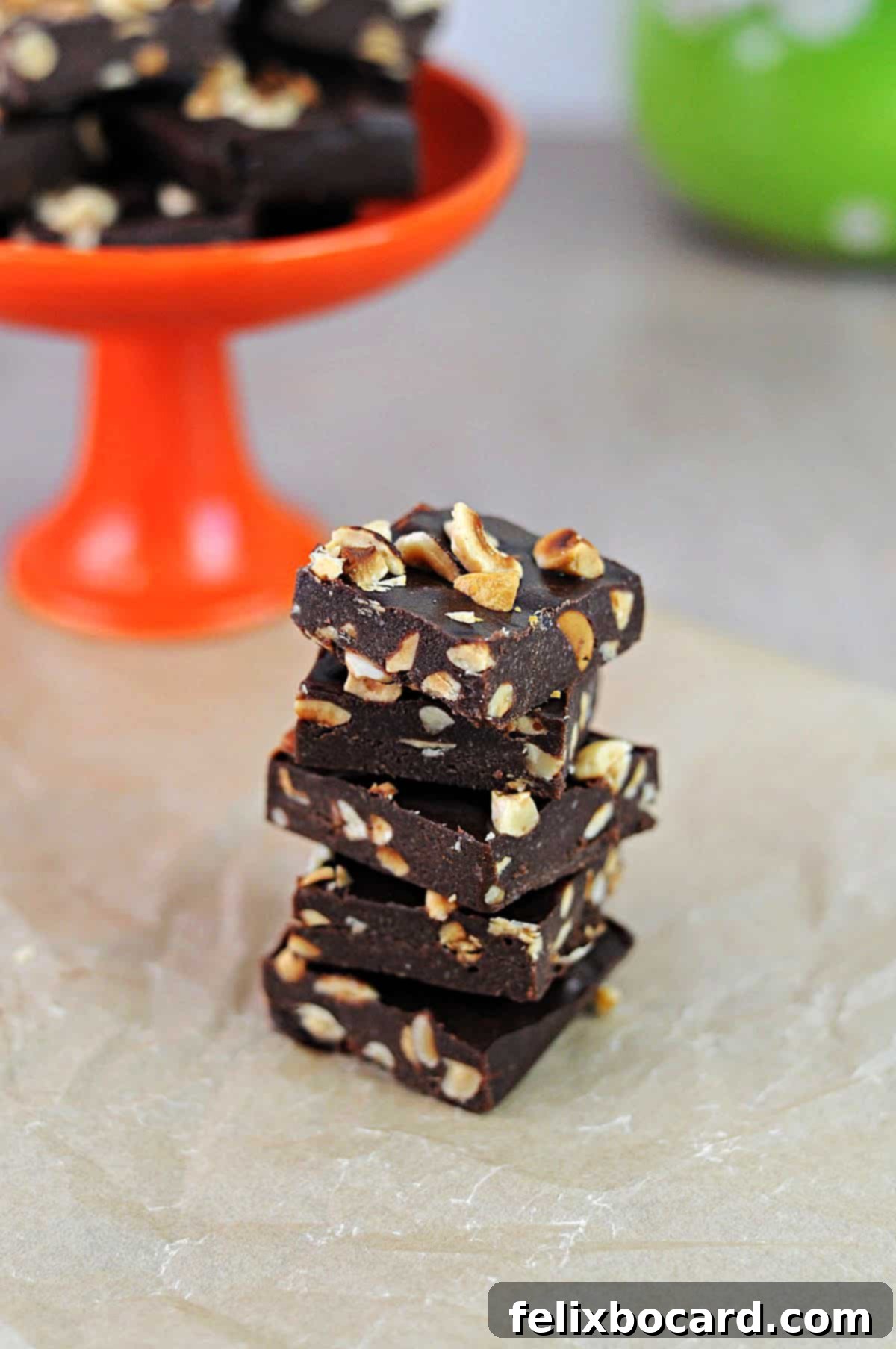 Stack of keto Nutella fat bombs, featuring a rich chocolate-hazelnut flavor, cut into squares and garnished with whole hazelnuts.